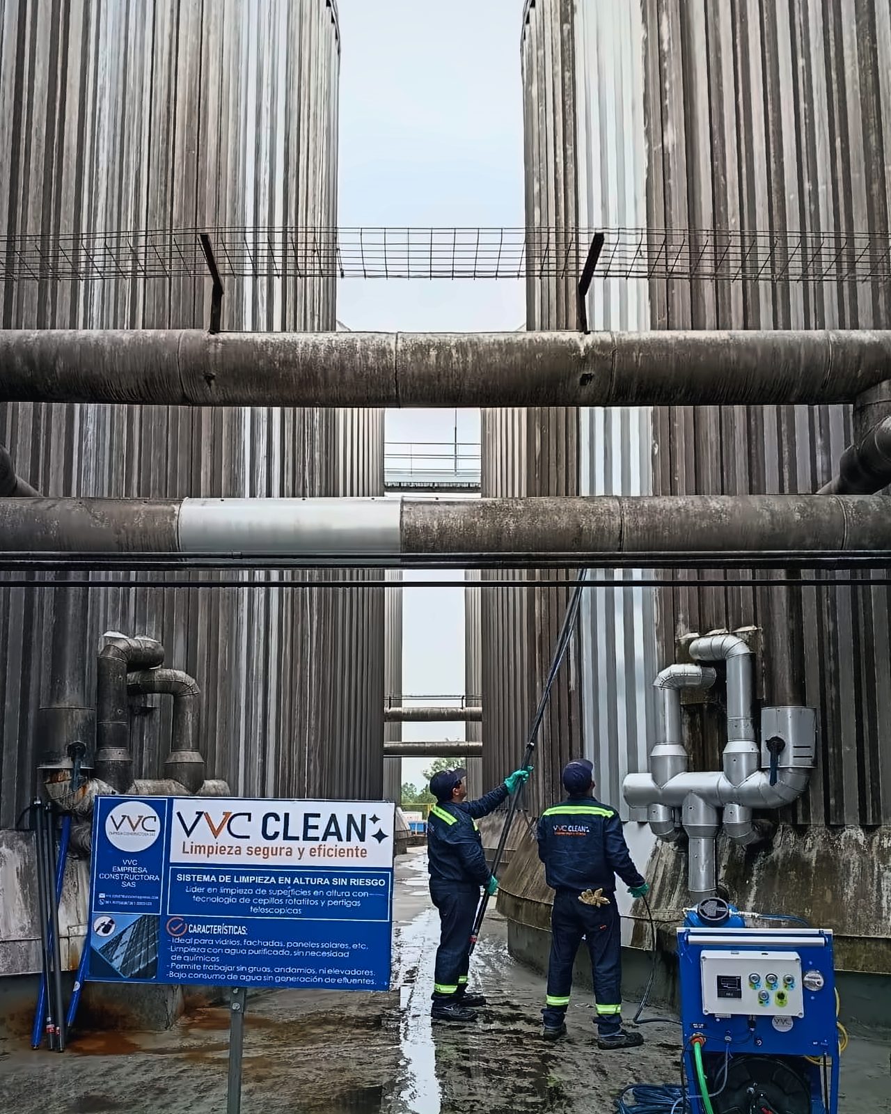 Dos operarios de VVC Clean con uniforme de la empresa limpian tanques con una pértiga; a la derecha, el carro azul de la planta de agua purificada y, a la izquierda, el cartel institucional.
